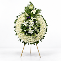 Couronne funéraire sur trépied, avec chrysanthèmes et lys blancs, palmes et feuillage vert.
