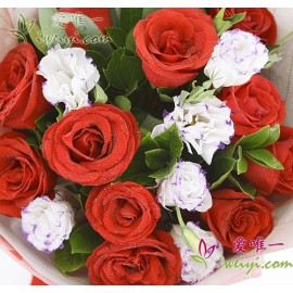 Bouquet composed of 11 red roses accented with white & purple lisianthus, iris leaves and fresh greens.