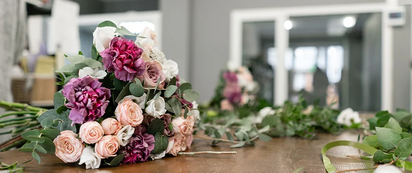 Roses fraîches, œillets et feuillage sur l’établi d’un fleuriste